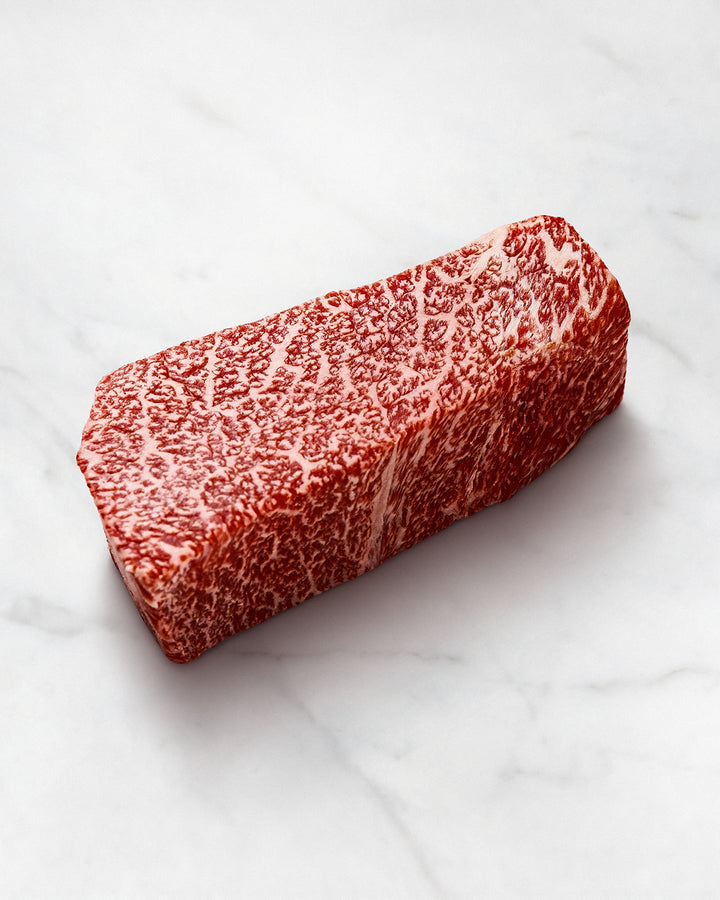 Wagyu-Teppanyaki-Steak extrem marmoriert auf weißem Hintergrund, Wagyu-Fleisch mit intensiver Marmorierung, vor dem Grillen in Tranchen schneiden