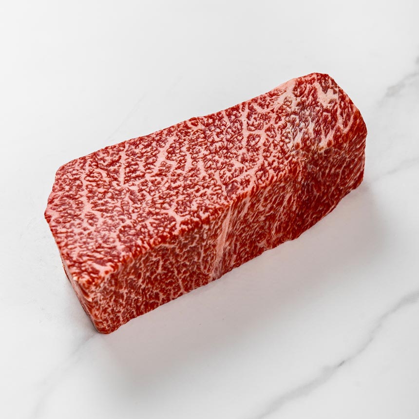 Wagyu-Teppanyaki-Steak extrem marmoriert auf weißem Hintergrund, Wagyu-Fleisch mit intensiver Marmorierung, vor dem Grillen in Tranchen schneiden